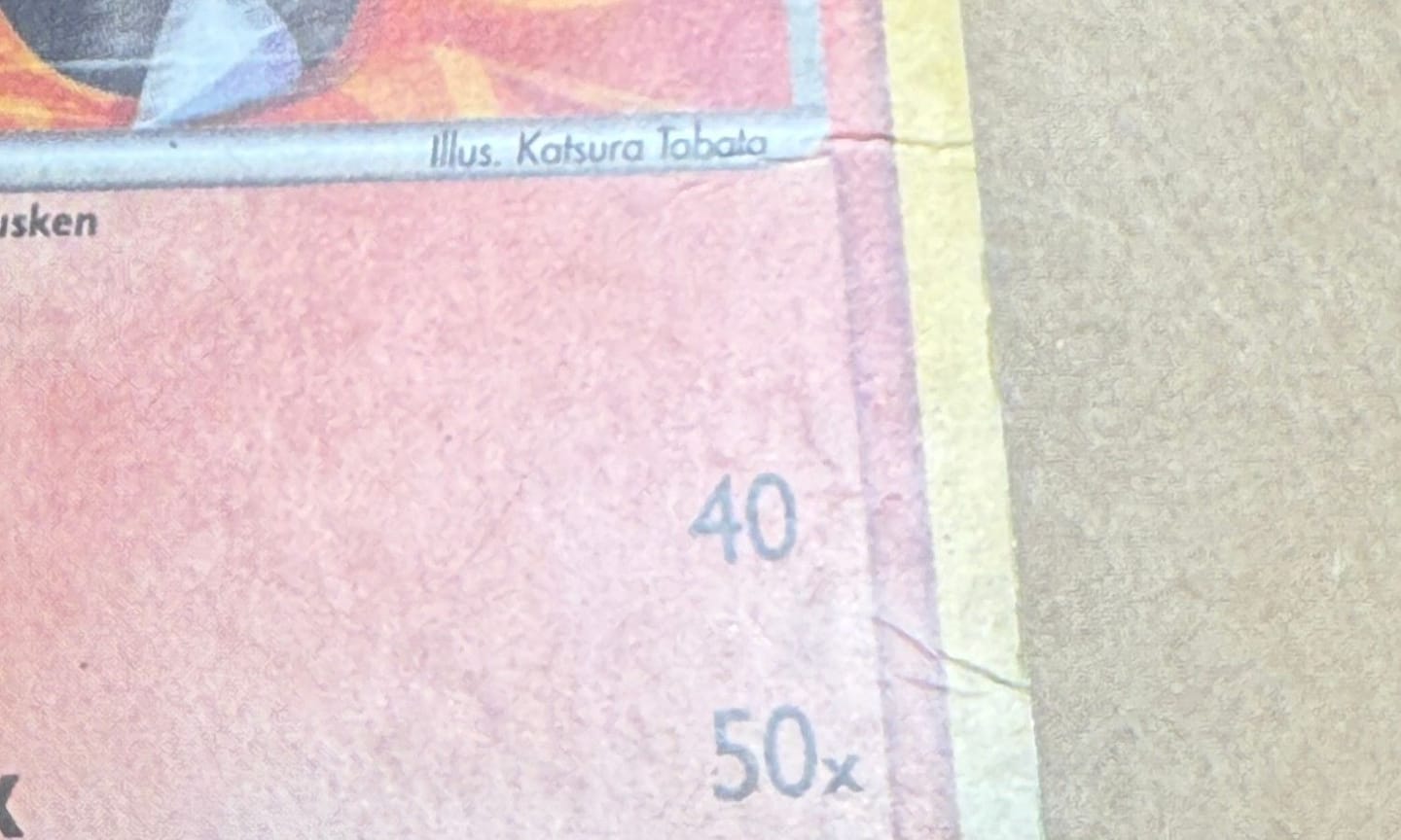 Close-up of the Blaziken card’s right edge before, two crease lines cracking across the red border and the yellow edge.